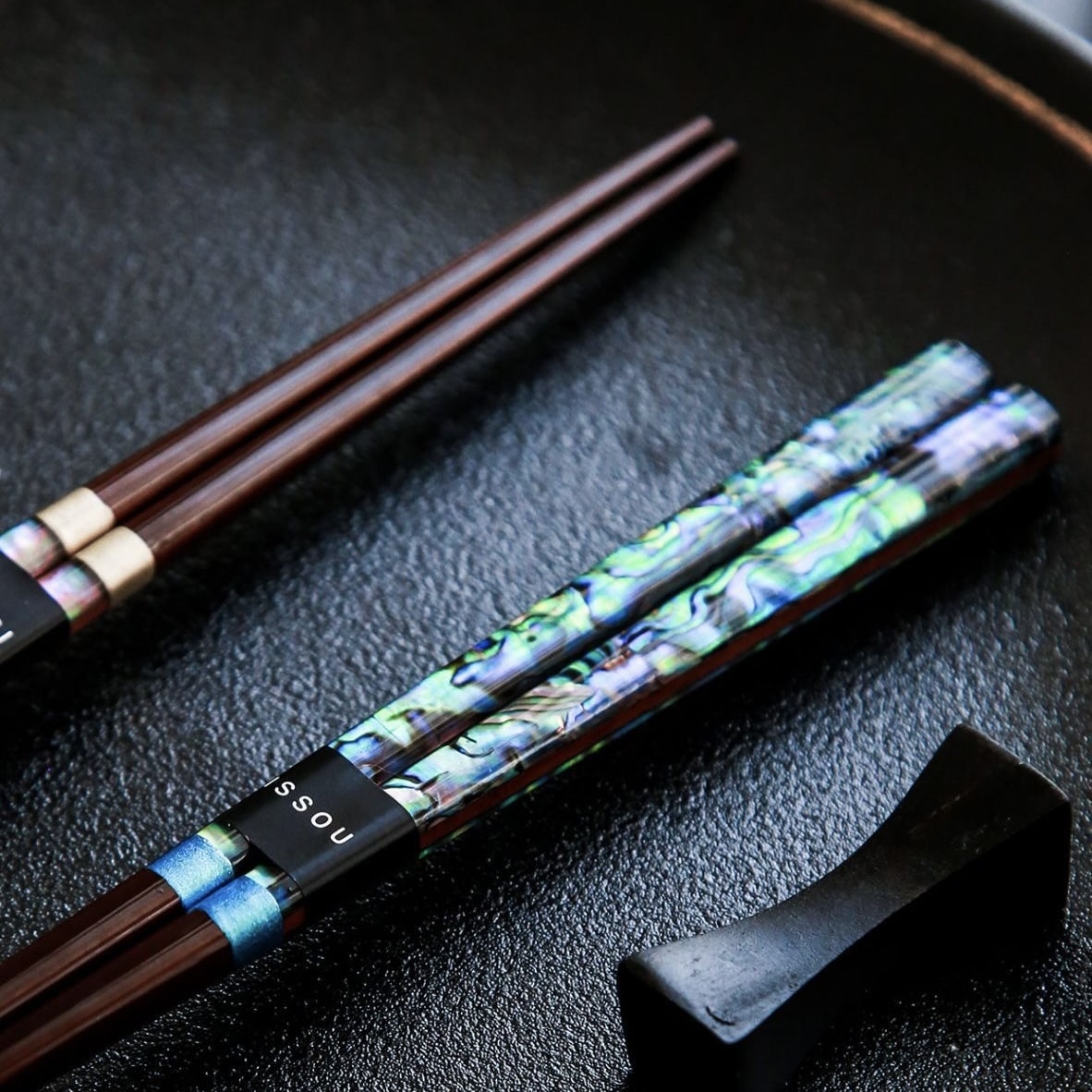 Elegant chopsticks with abalone shell design on black background