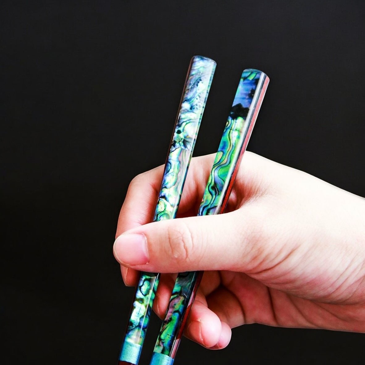 Elegant chopsticks with abalone shell design on black background