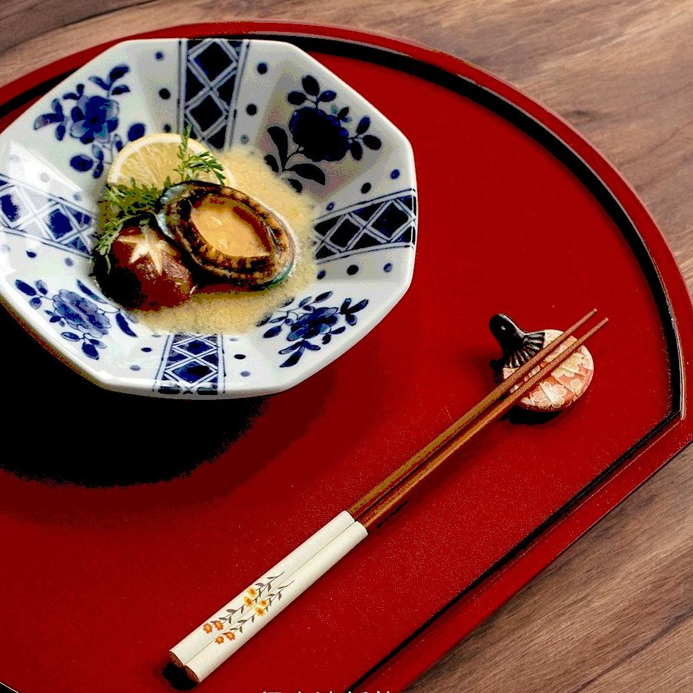 Hand holding a floral chopstick set above a rice bowl