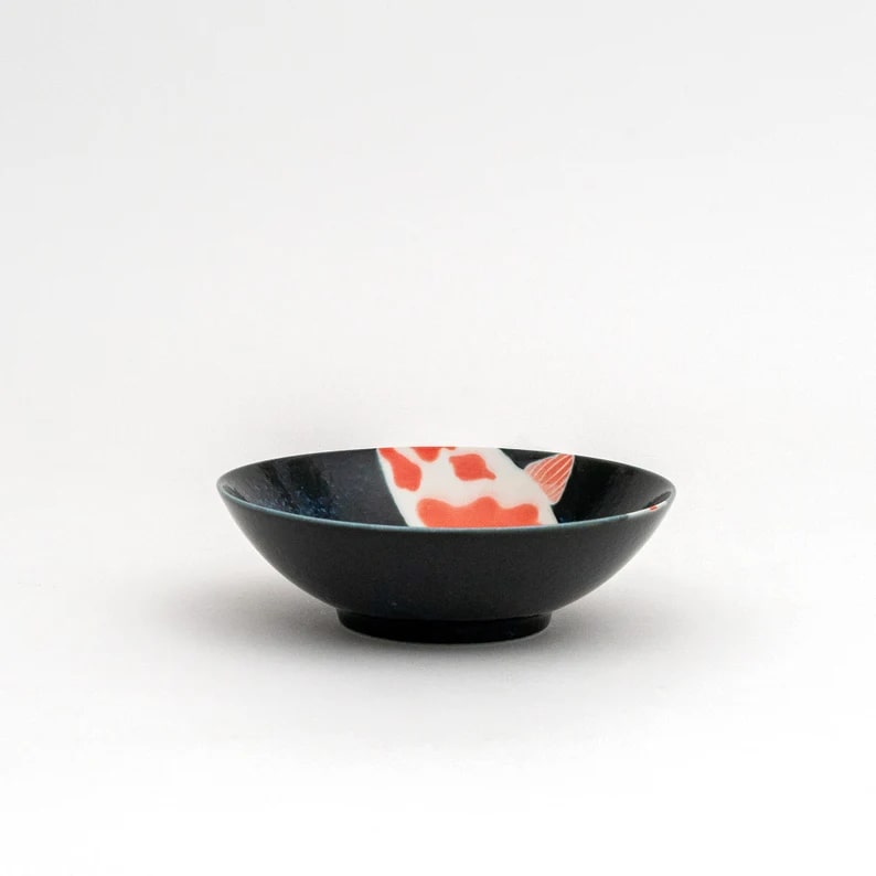 Ceramic dinnerware featuring koi fish patterns in navy blue.
