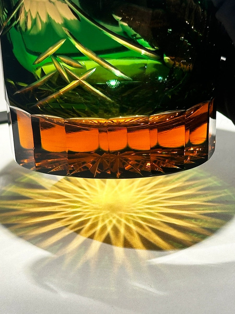 Close-up of Japanese crystal whiskey glass featuring intricate Mount Fuji and palace details in blue and green.
