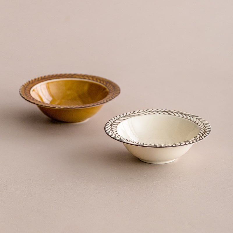 Flat white ceramic plate with leaf pattern rim on wooden table