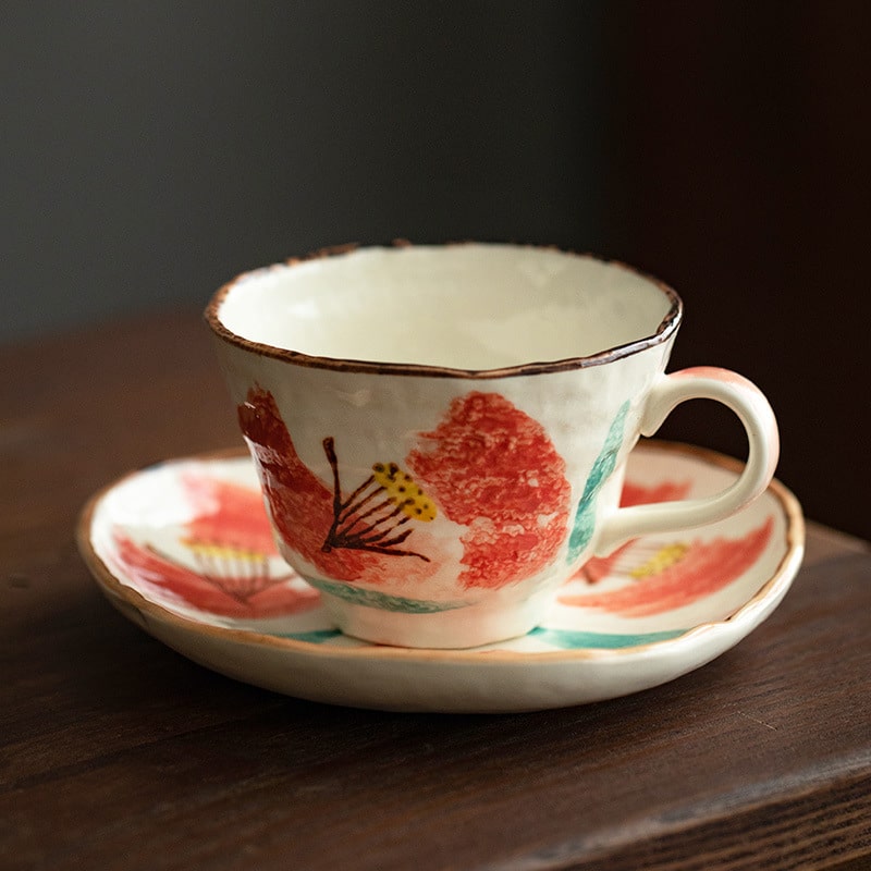 Red floral artisan tea cup set on rustic wooden table