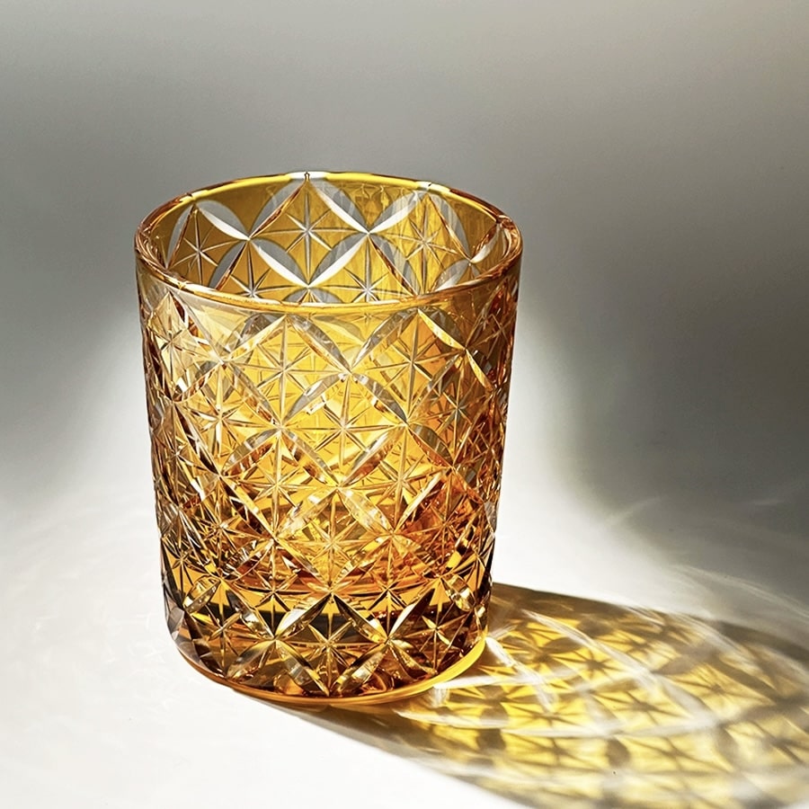 Amber hand-carved "Seven Treasures" crystal whiskey glass with intricate starburst design, perfect for whiskey lovers.