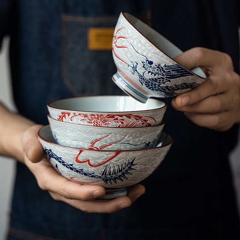 Stack of ornate dragon-themed bowls held in hands