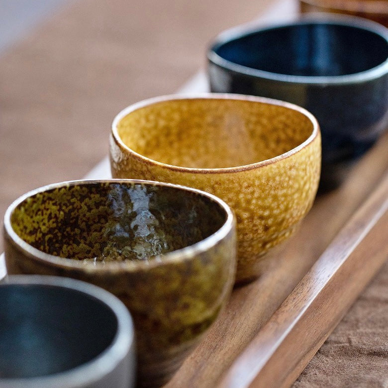 Close-up of tea cups and saucers arranged on a wooden table.