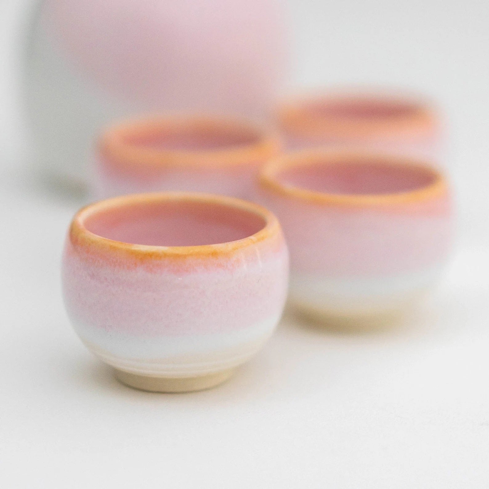 Blush-pink sake set with four matching cups on white background