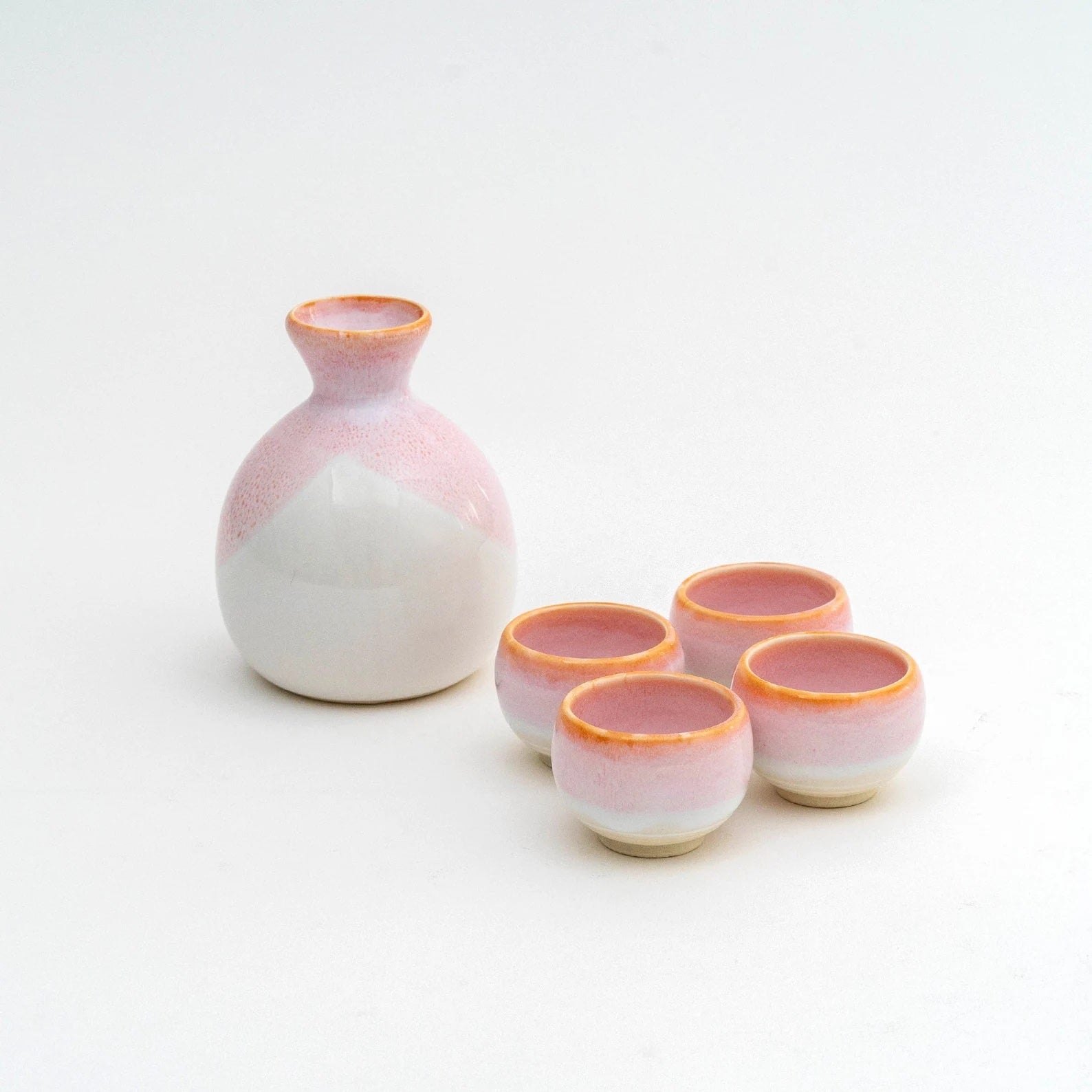 Blush-pink sake set with four matching cups on white background