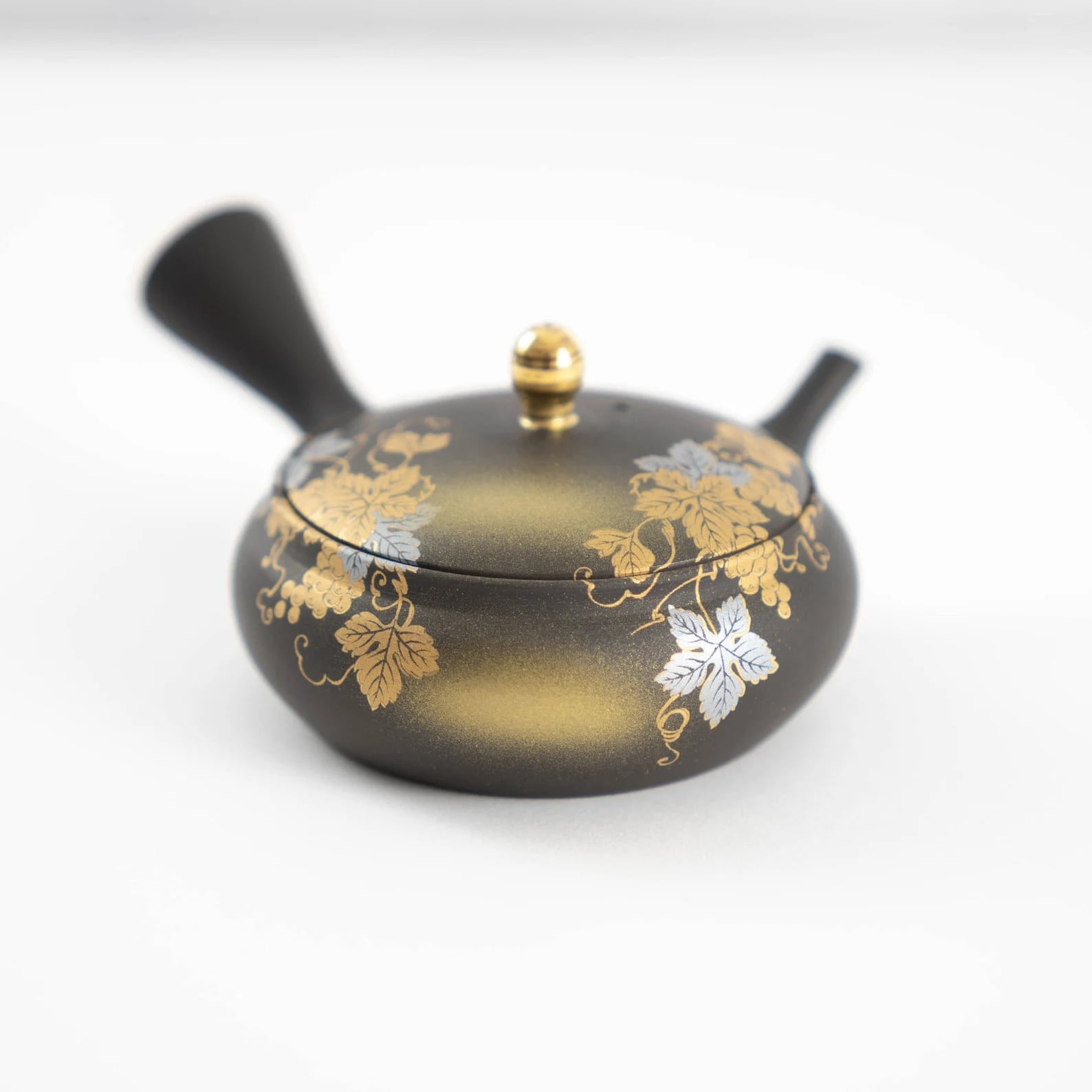 Hand-painted Japanese kyusu teapot beside elegant sake cups