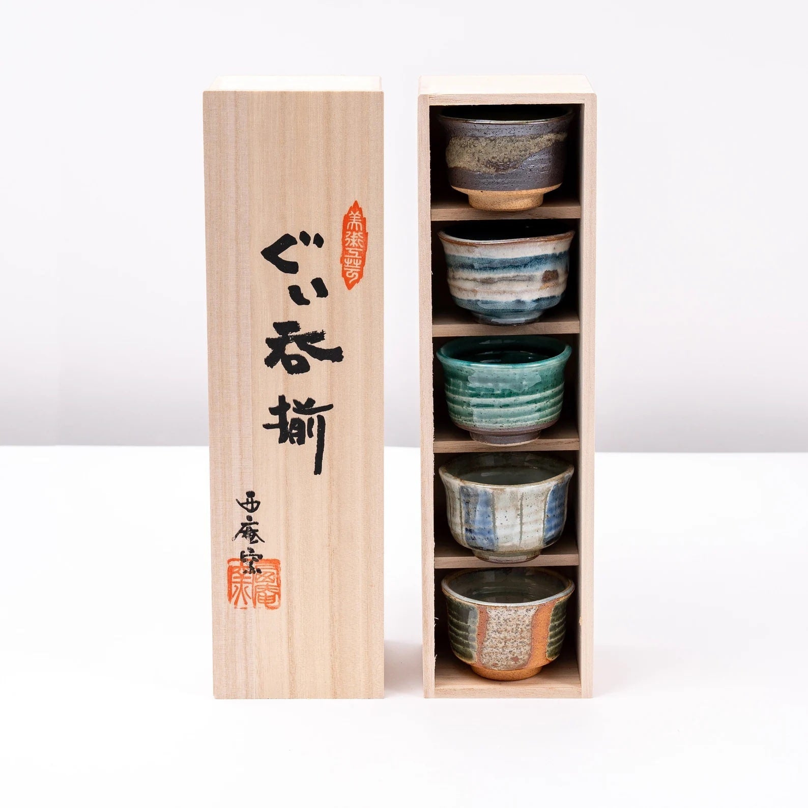 Elegant wooden box containing artisan sake cups in various designs