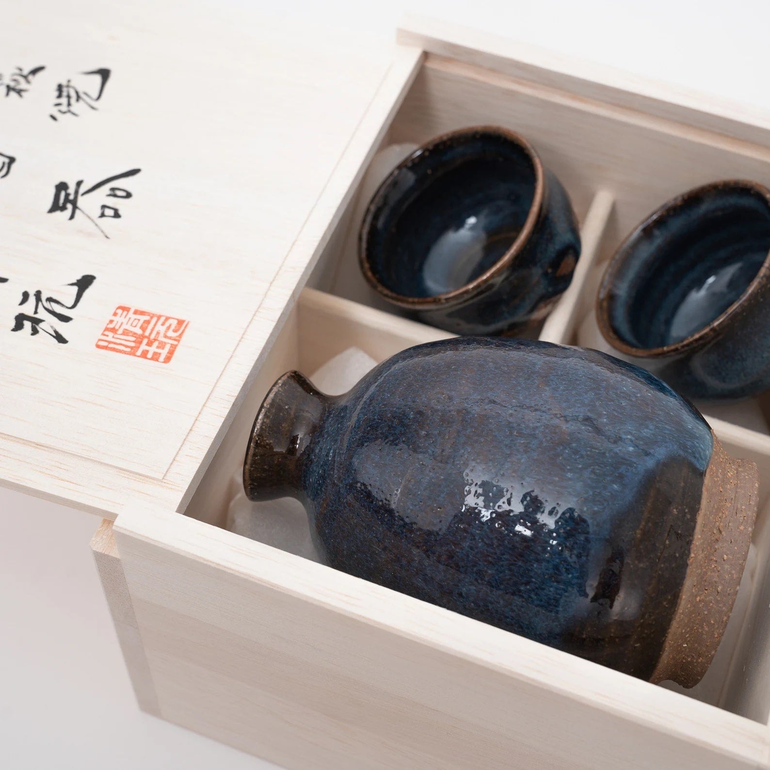 Close-up of dark-toned sake cup set revealing subtle texture