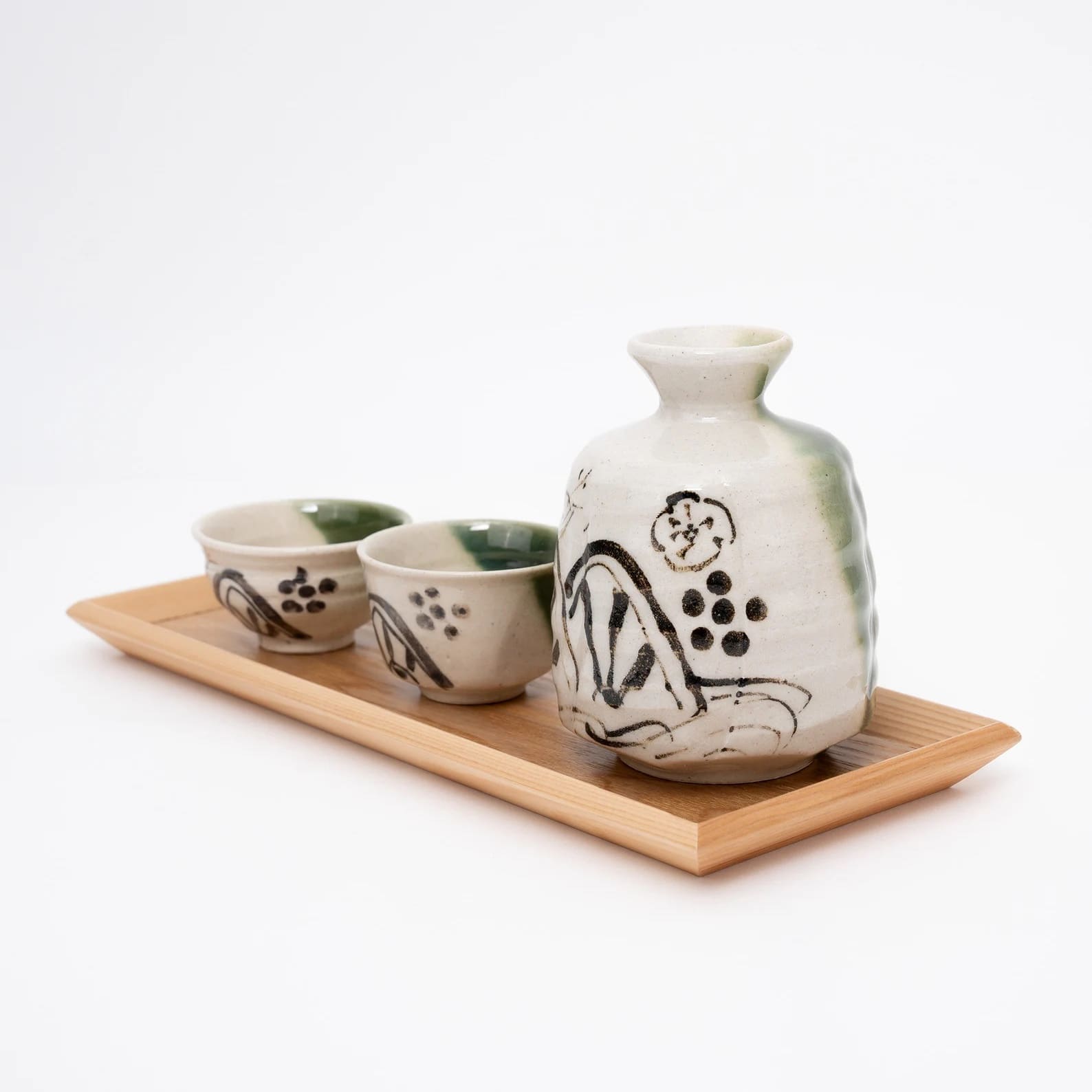 Two sake cups paired with a matching sake carafe on a wooden tray