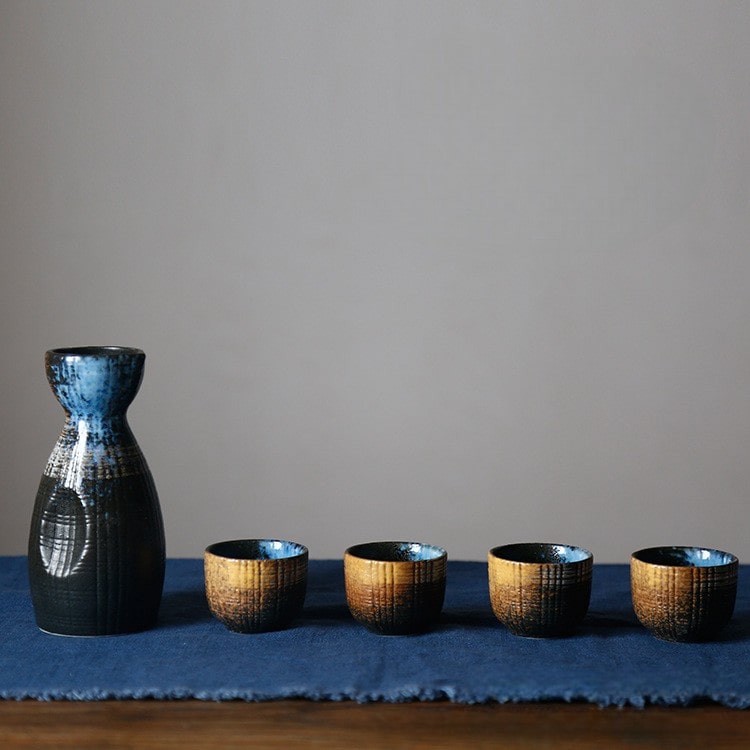 Rustic sake set with earthy and blue tones on a wooden table.
