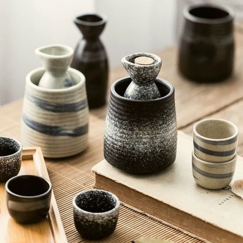 Rustic speckled ceramic sake set with bottle and matching cups.
