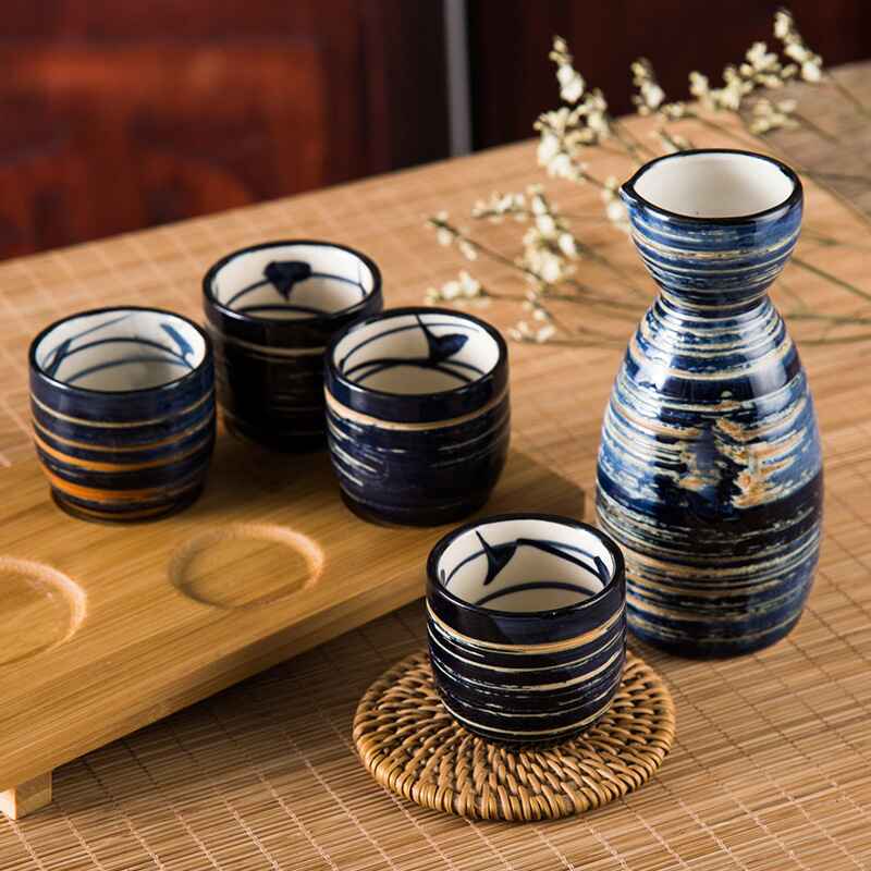 Elegant ceramic sake set with striped and floral patterns in navy tones.
