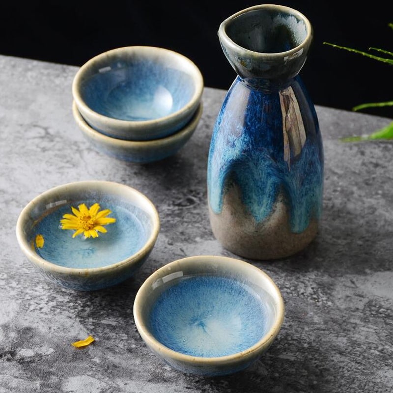 Elegant blue and earthy-toned ceramic sake set on a dark table.
