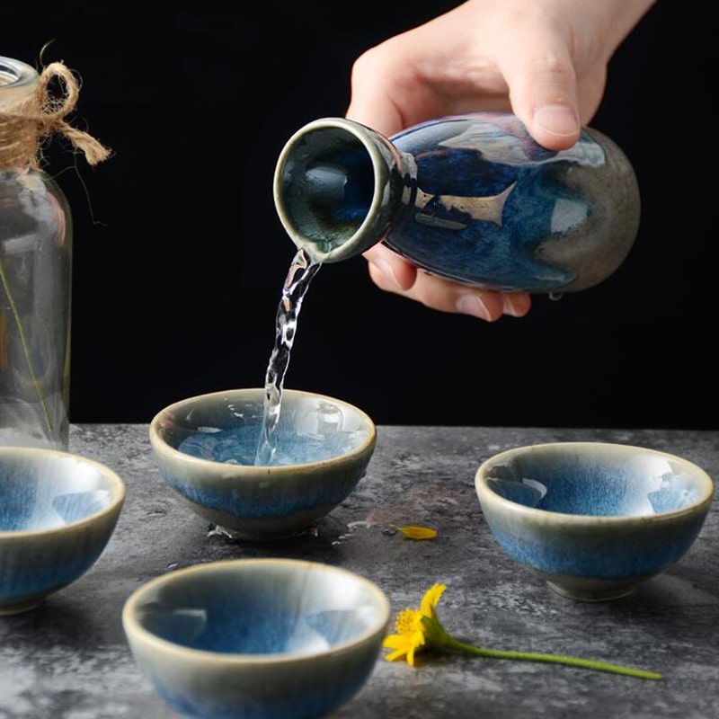 Handcrafted sake drinking set featuring a bottle and wide shallow cups.
